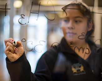 student doing math at a clear board