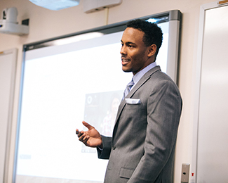 student in a suit in front of a powerpoint