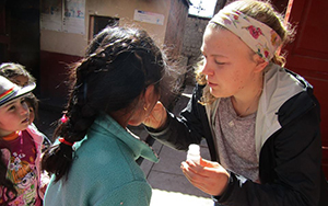 student administering medicine to a child in Peru