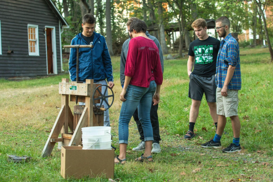 Students gathering in parkwoods to press apples for cider at a cider press Students gathering in parkwoods to press apples for cider at a cider press